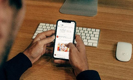 Worker looking at smartphone at desk with keyboard and mouse